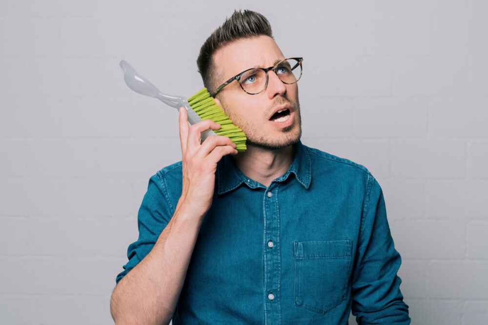 Matthias Hauser hält einen Besen an sein Ohr